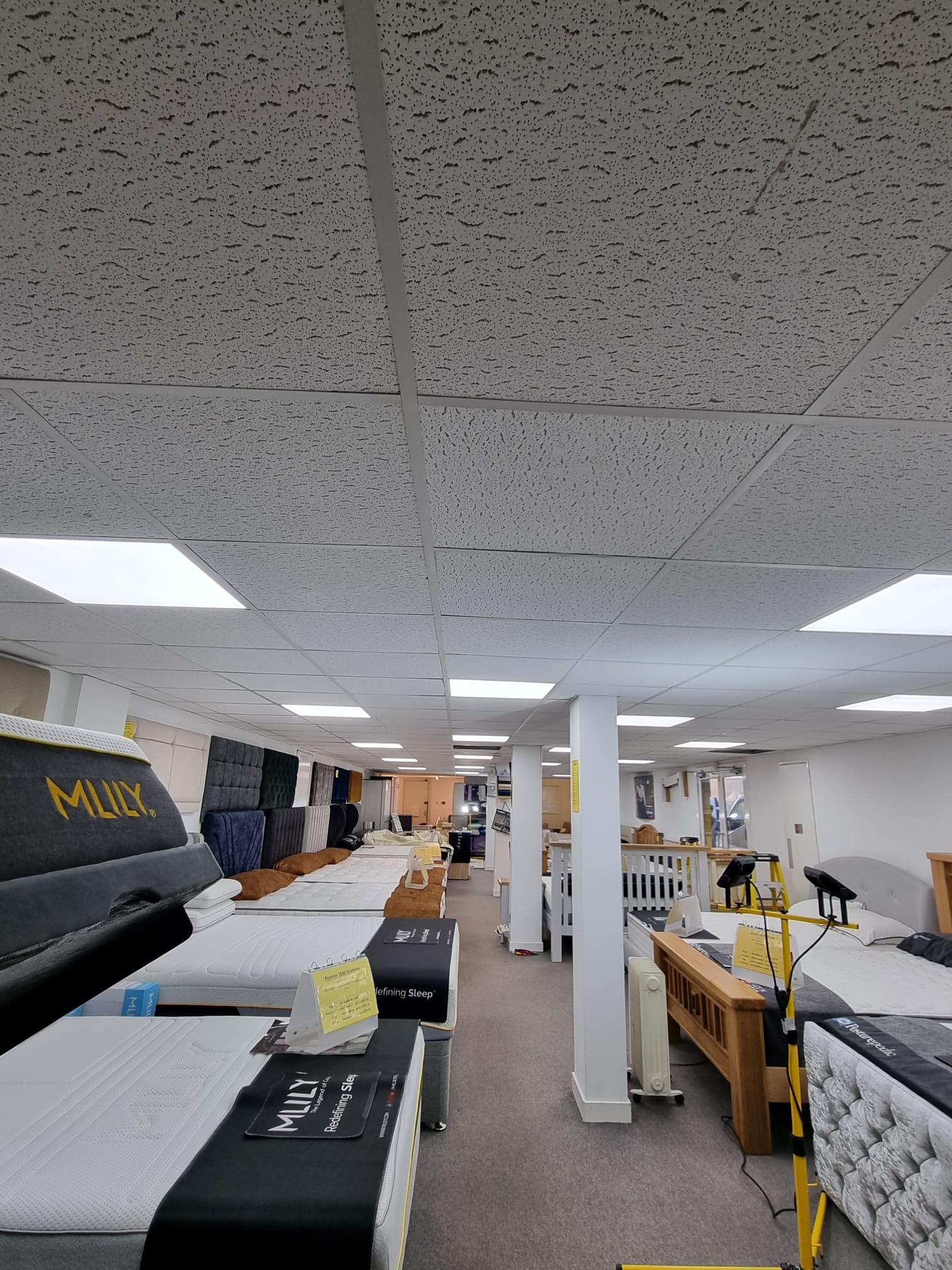 A well-lit room with a high ceiling from which rows of lights are suspended