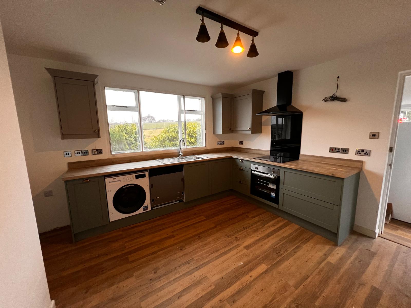 A modern kitchen bathed in natural light from a large window that offers a serene view of trees outside