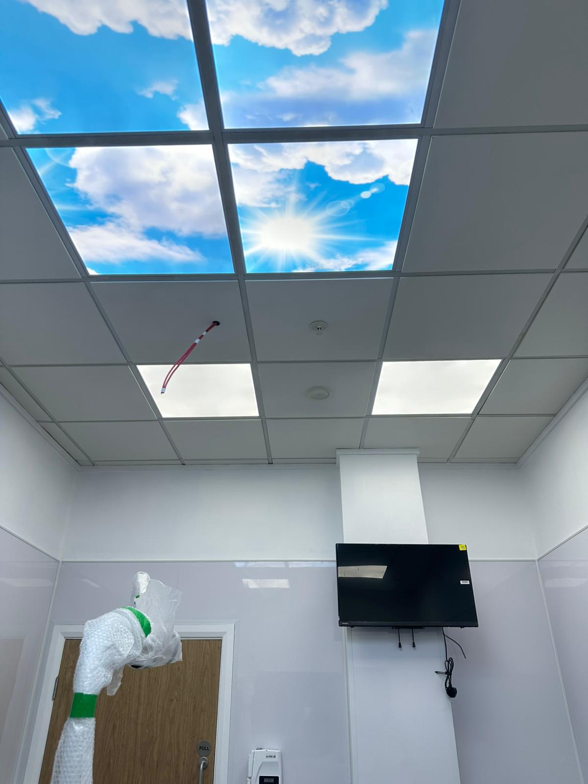 A room with a unique ceiling design that resembles a blue sky dotted with white clouds