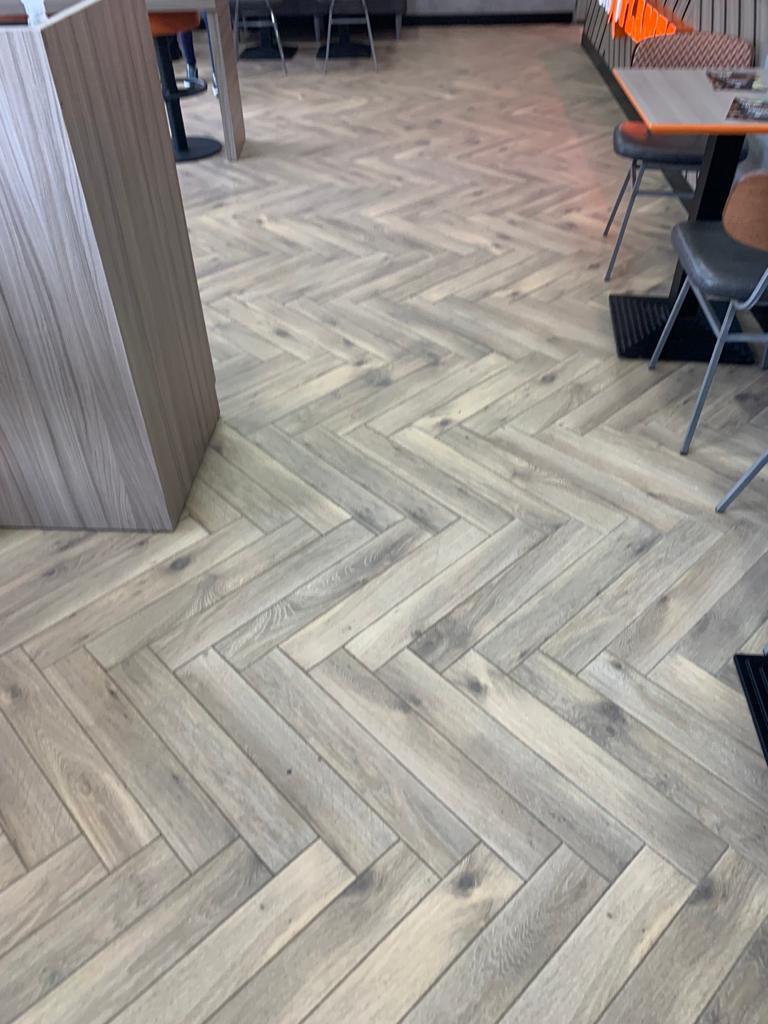 A cozy restaurant interior, bathed in soft light that accentuates the warm tones of the wooden floor and furniture